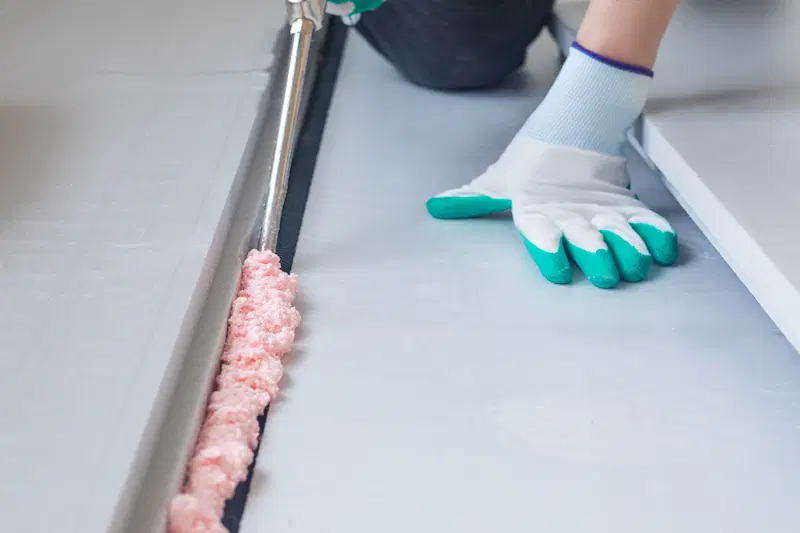 Worker applying foam adhesive for insulation