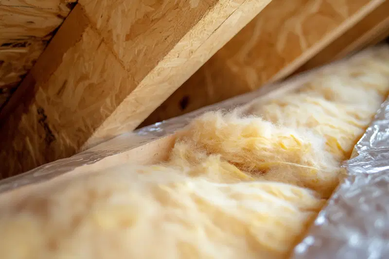 Yellow fibreglass insulation installed in wooden frame